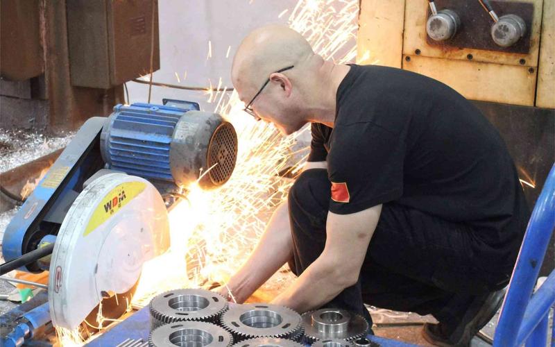 JC Packs technician grinding a machined component, sparks flying, in the workshop